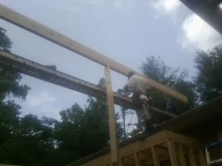 Carpenter setting a ridge beam over a new addition frame — Ice Dam Removal by Roofing Brothers in Follansbee