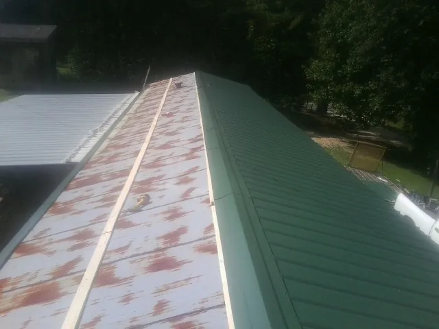 Old rusted panels beside newly installed green metal roofing — Wind Damage Roof Repair by Roofing Brothers in Follansbee