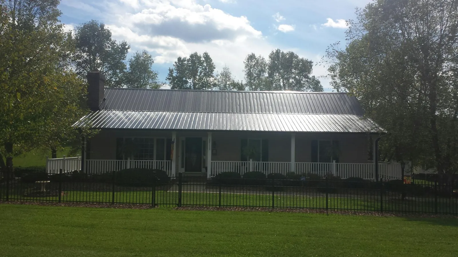 Gray metal roof on a brick ranch with a full width front porch — Gutter Guard Installation work by our crew in Follansbee