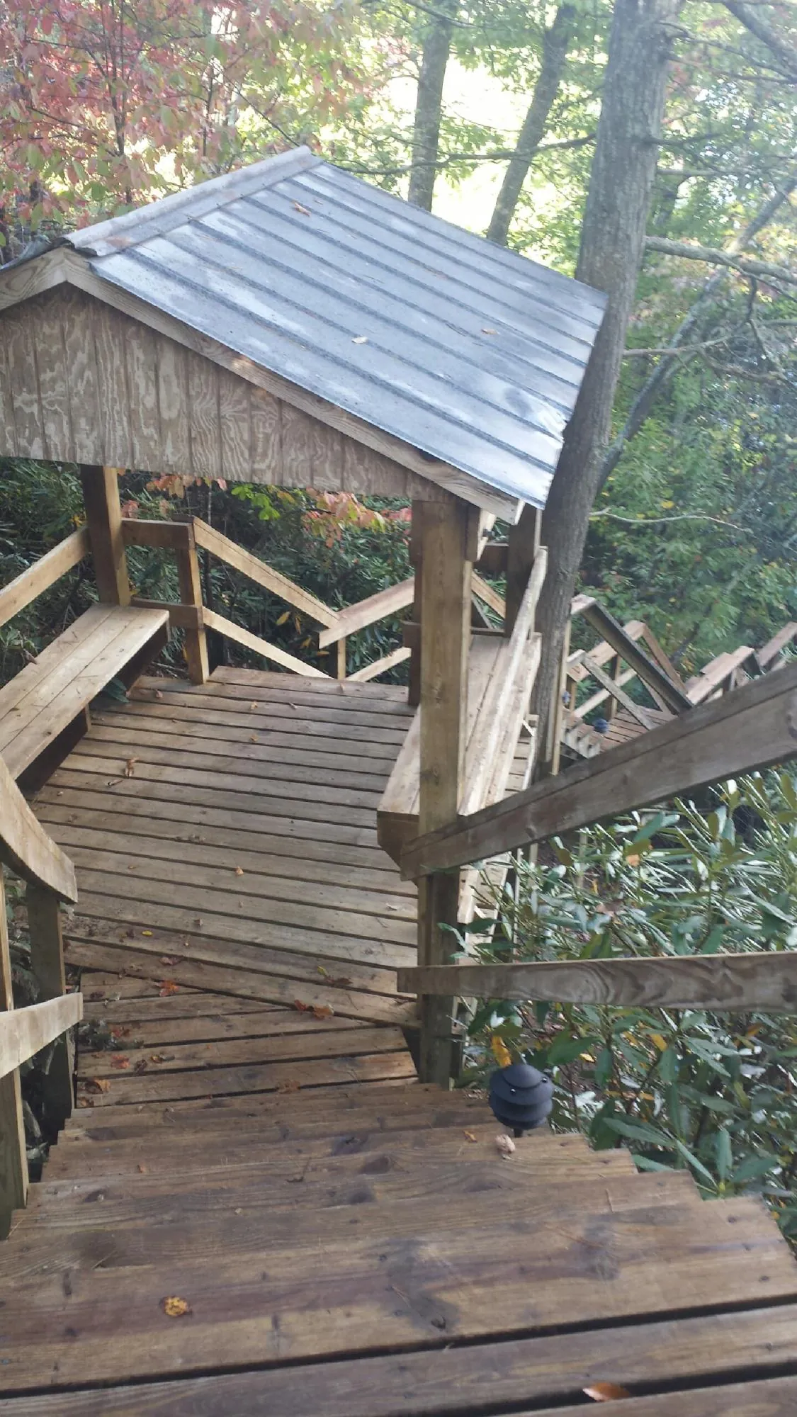 Metal roofed shelter over wooden steps on a wooded walkway — Skylight Repair & Installation work by our crew in Follansbee