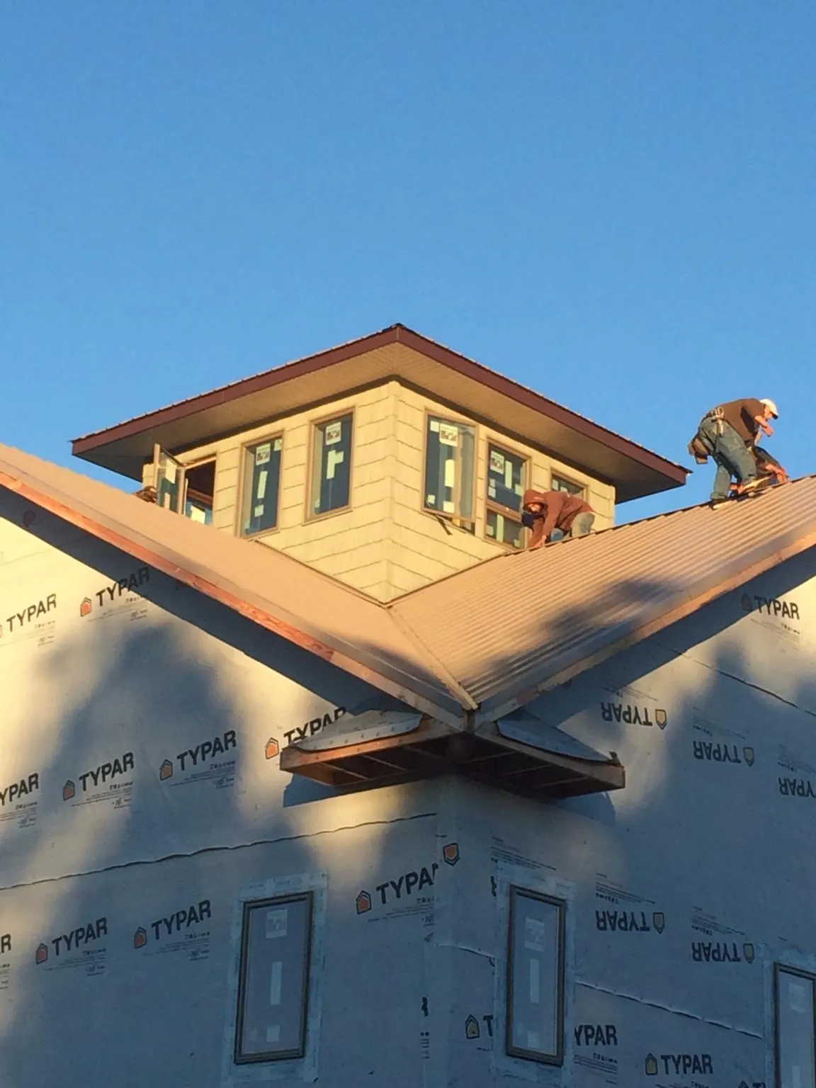 Roofers working around a rooftop cupola on a new metal roof at sunset — Roof Waterproofing in Follansbee by Roofing Brothers